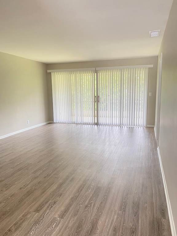 A room with wooden flooring and a window with blinds.