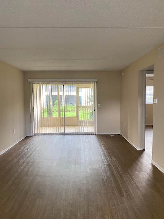 A room with wooden floors and a sliding glass door leading to a balcony.