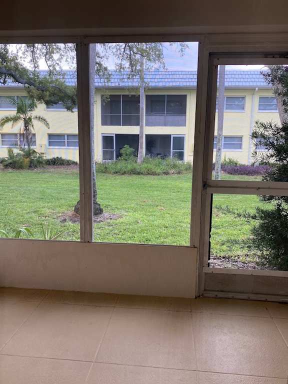 A view of a building through a window with a tree in the foreground.