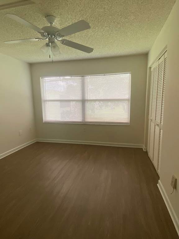 A room with a ceiling fan and a window with blinds.
