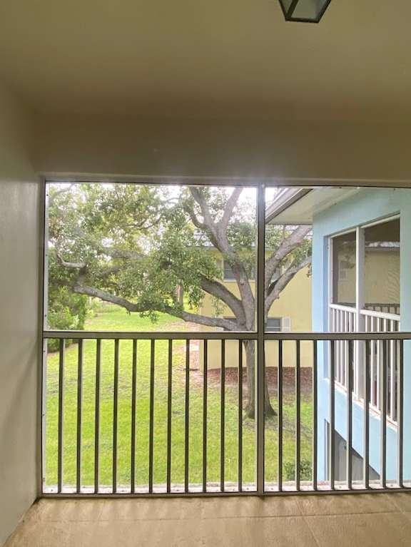 A balcony with a metal railing overlooking a green lawn and trees.