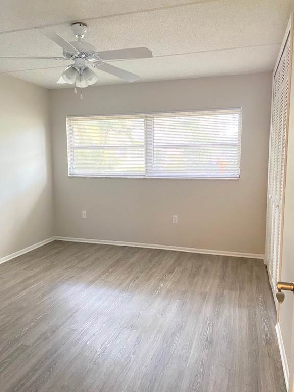 A room with a ceiling fan and a window with blinds.