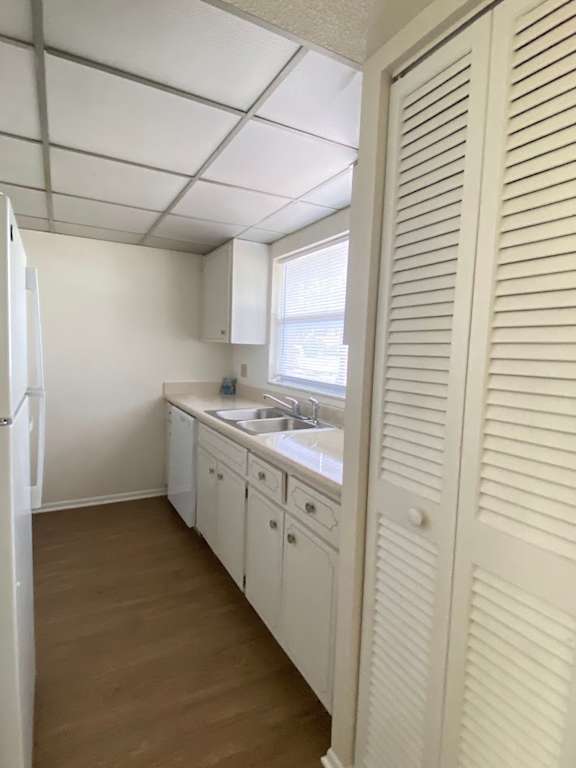 A kitchen with white cabinets and a white fridge.