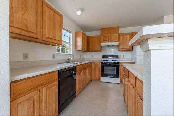 a kitchen with wood cabinets and black appliances and white counter tops  at Huntington Village **, Warner Robins, 31098
