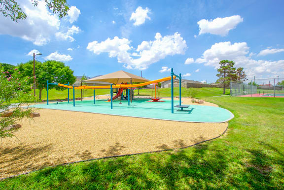 a playground with a blue and yellow swing set on a sunny day  at The Village at Cottonwood Springs, Texas