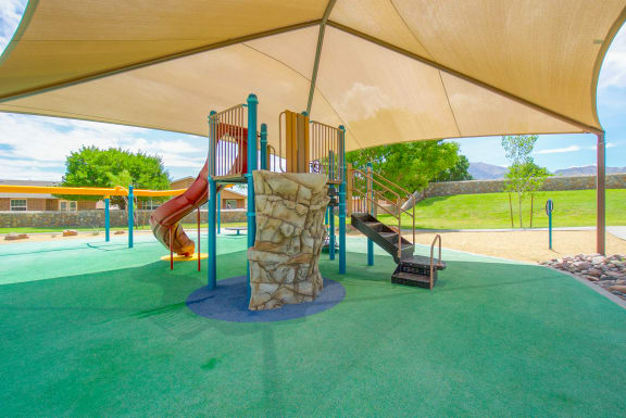 a playground with a slide and other play equipment under a tent  at The Village at Cottonwood Springs, El Paso, 79934