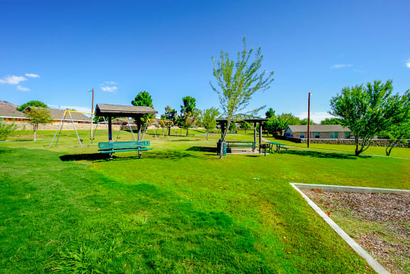 a playground with two swings and a swing set in a park  at The Village at Cottonwood Springs, Texas