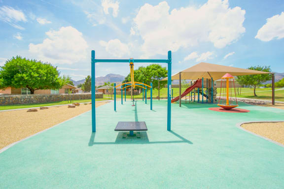 a playground with a swing set and a picnic table  at The Village at Cottonwood Springs, El Paso, TX, 79934