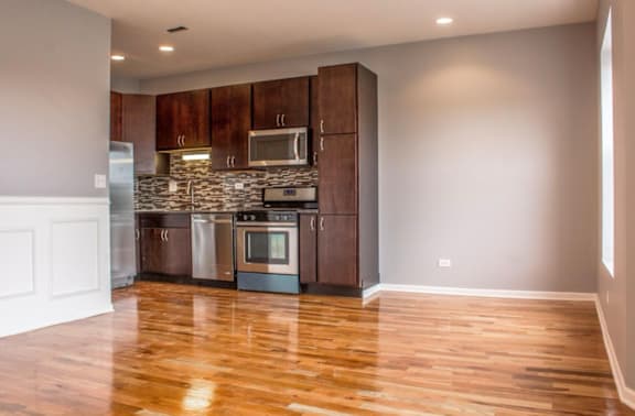 A kitchen with wooden floors and a white wall.