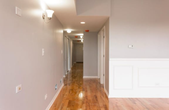 A long hallway with white walls and wood floors.