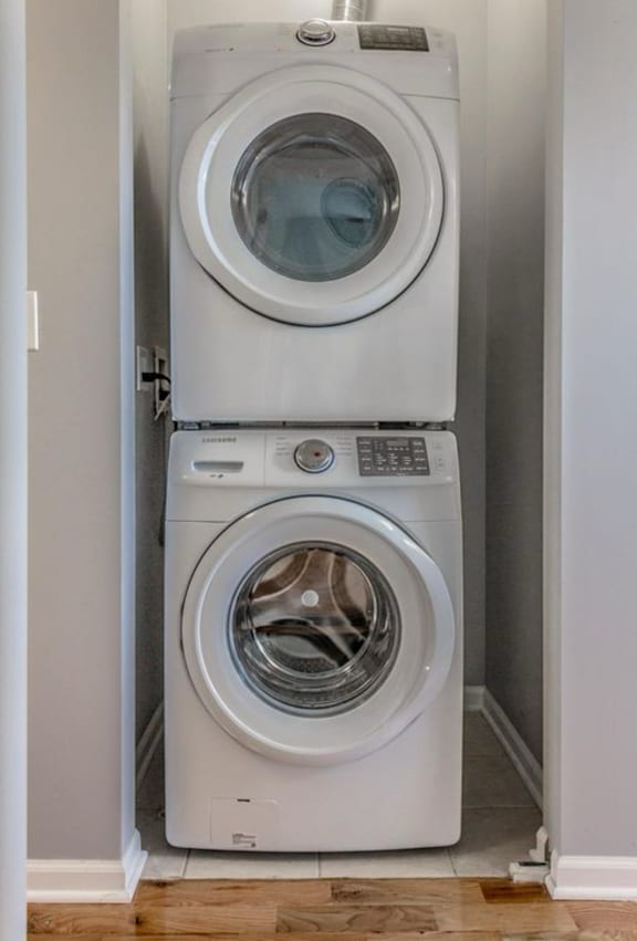 A white front load washing machine is stacked on top of another white front load washing machine.