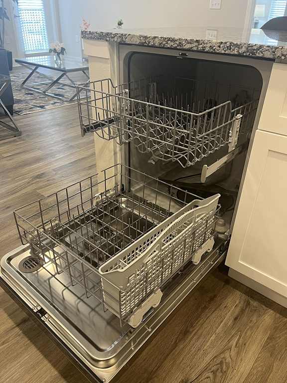 A dishwasher with its door open and racks inside.