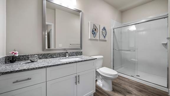 A bathroom with a toilet, sink, and mirror.