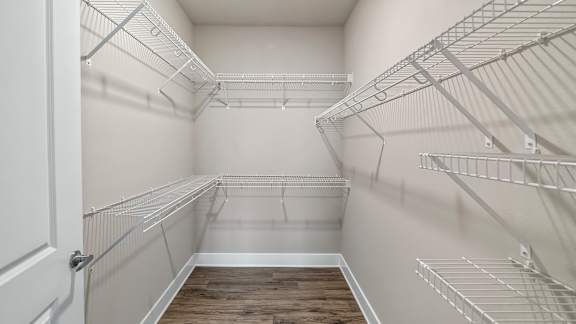 Empty walk-in pantry with white walls and shelving.