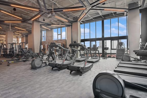 Impressive gym loaded with next-gen workout equipment and equipment with large windows for an abundance of natural lighting at Post District Residences in Downtown Salt Lake City, Utah