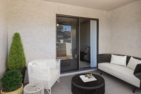 a patio with a white couch and a black coffee table