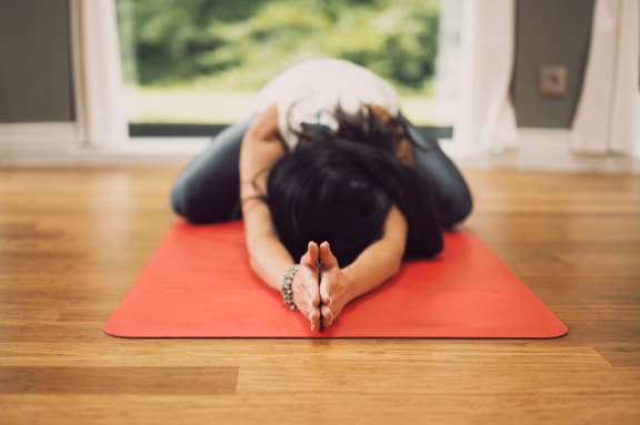 a woman lying on a yoga mat with her head down