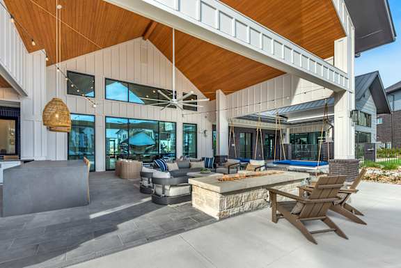 A modern house with a wooden roof and a patio with chairs.
