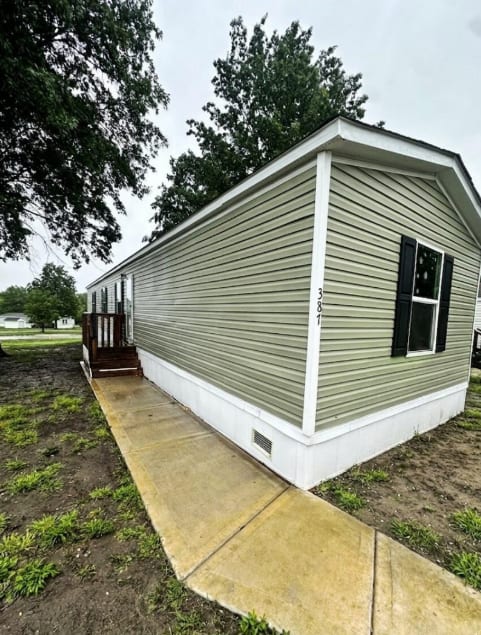 A small house with a grey siding and a black window is shown.