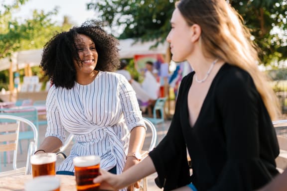 two women sitting at a table with beers