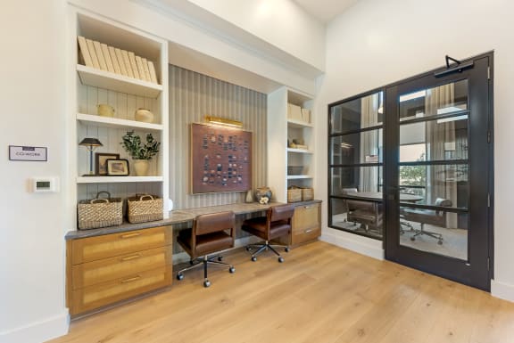 a home office with a large window and a desk with two chairs