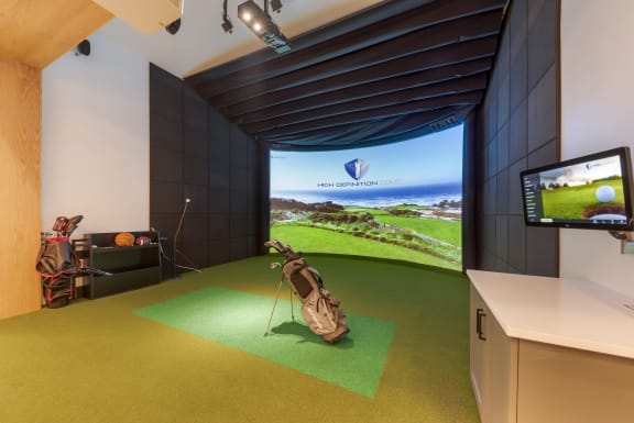 a golf simulator in a room with a tv and a golf bag