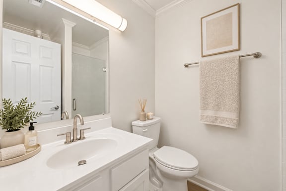 A white bathroom with a toilet, sink, and towel rack.