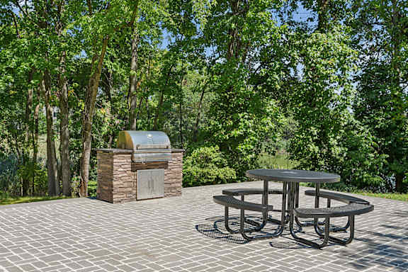 A picnic table is surrounded by trees and a stone structure.