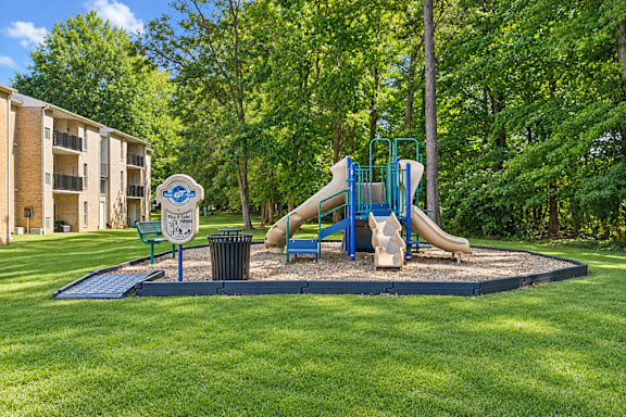 A playground with a blue slide and a sign in the foreground.
