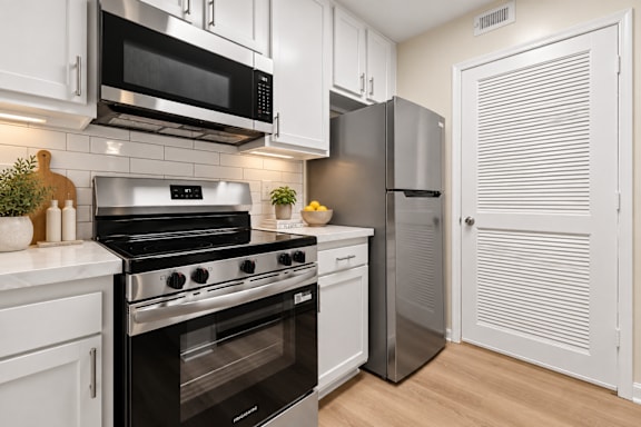 Modern kitchen with stainless steel appliances and white cabinetry at The Courts at Fair Oaks Apartments, Virginia