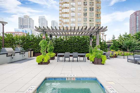A pool with a 3 feet deep sign is surrounded by a patio with chairs and a pergola.