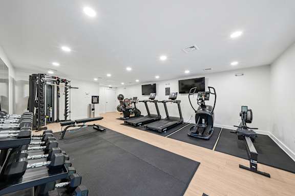 A well-lit gym with a variety of equipment including treadmills, weights, and exercise machines.