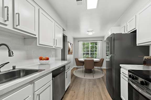 A modern kitchen with white cabinets and a black refrigerator.