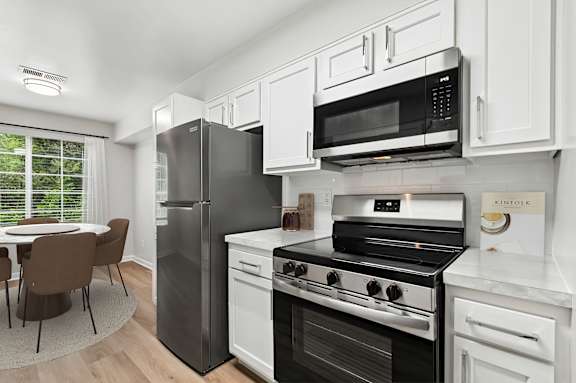 A kitchen with a black fridge, stove, and microwave.