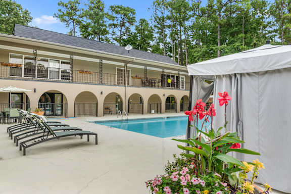 A pool area with sun loungers and a building in the background. at Riverchase Landing, Hoover, AL