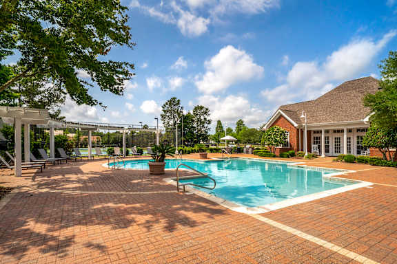 A large outdoor swimming pool surrounded by a brick patio.