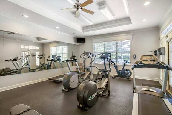 A spacious gym with a variety of exercise equipment and a ceiling fan.
