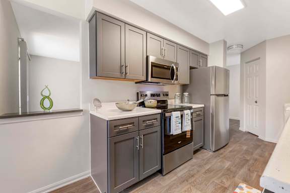 A kitchen with dark brown cabinets and stainless steel appliances. at The Apartments at Owings Run, Owings Mills