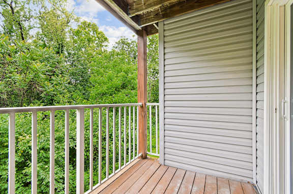 A wooden deck with a white railing and a sliding door.
