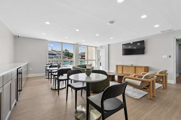 A modern dining area with a table set for six and a television mounted on the wall.