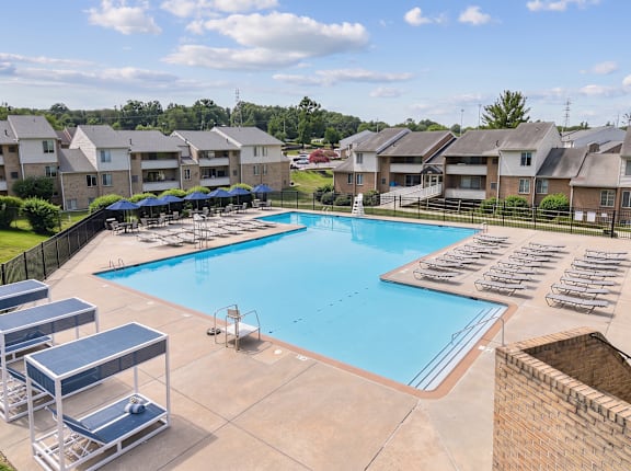A swimming pool surrounded by sun loungers and apartment buildings.