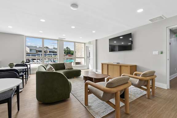 A living room with a green chair and a television on the wall.