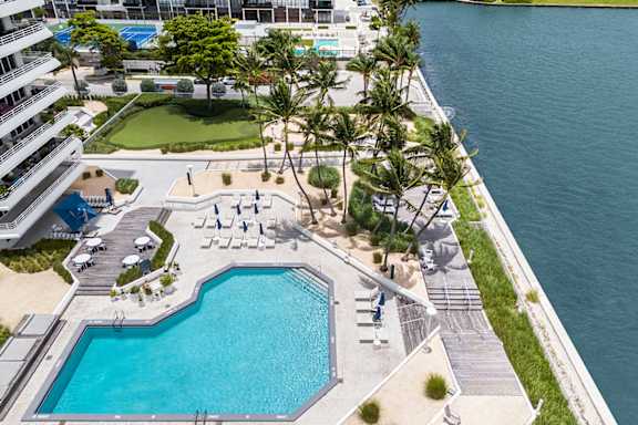 Waterfront pool deck with lounge chairs and palm trees at The Hamilton Apartments, Miami, FL