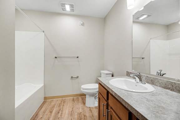 A white toilet sits in a bathroom with a sink and a bathtub.