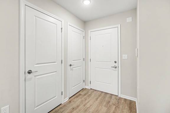 Three white doors in a hallway with wood flooring.