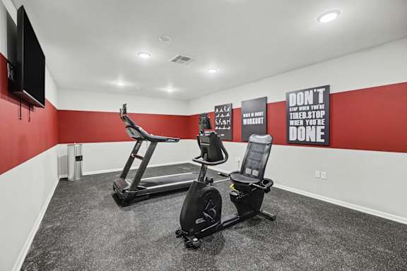 A gym room with a treadmill and a stationary bike.