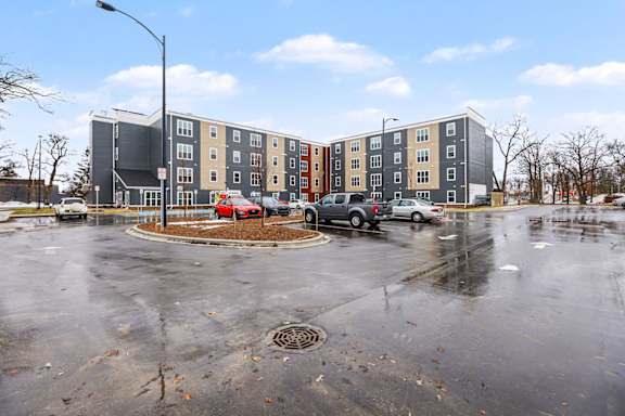 A parking lot in front of a multi-story apartment building.