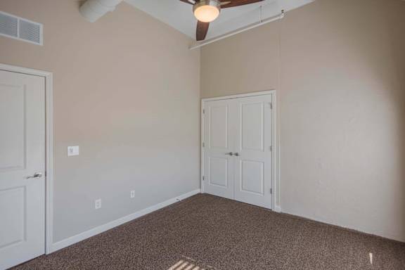 A room with a carpeted floor and a ceiling fan.