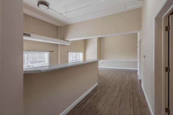 A long, empty hallway with wooden floors and white walls.