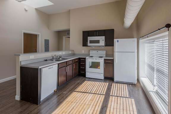 A kitchen with white appliances and wooden floors.